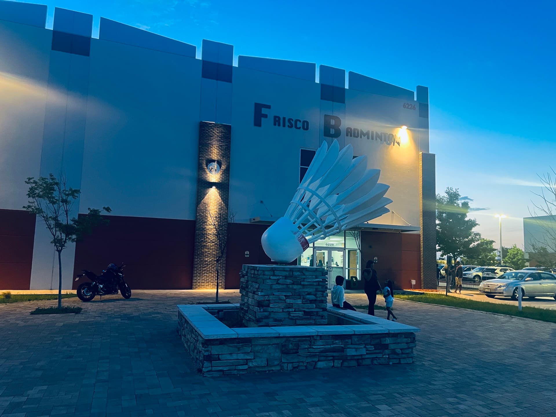 The giant shuttlecock sculpture outside Frisco Badminton Academy at dusk